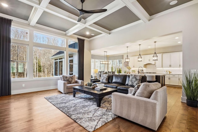 living area featuring baseboards, beamed ceiling, hardwood / wood-style flooring, coffered ceiling, and a ceiling fan