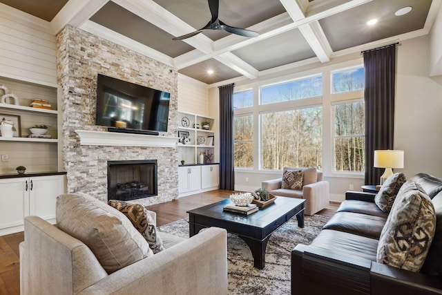 living area with beam ceiling, a fireplace, wood finished floors, coffered ceiling, and a ceiling fan