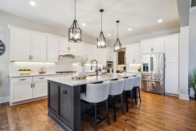 kitchen featuring white cabinets, wood finished floors, appliances with stainless steel finishes, and a sink