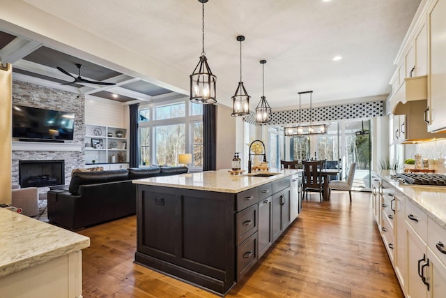 kitchen with coffered ceiling, a sink, hardwood / wood-style flooring, white cabinets, and ceiling fan with notable chandelier