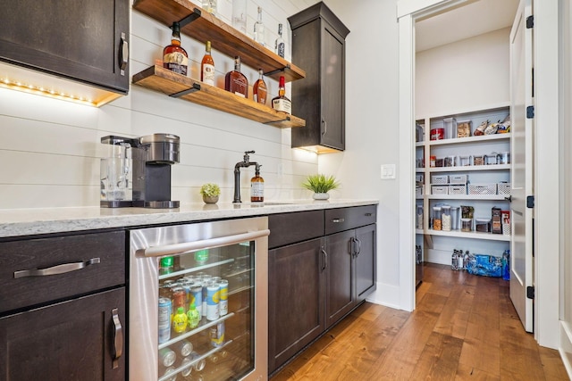 bar featuring beverage cooler, hardwood / wood-style flooring, a sink, backsplash, and a bar