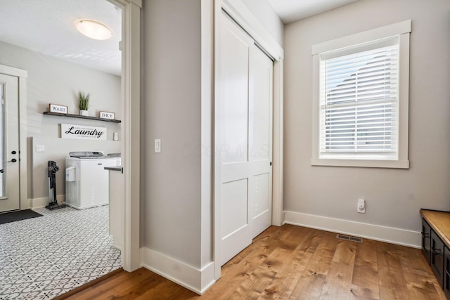 interior space featuring visible vents, light wood-style flooring, washing machine and dryer, and baseboards