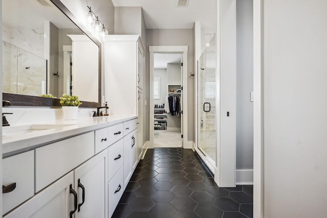 bathroom featuring tile patterned floors, a stall shower, a sink, double vanity, and a spacious closet