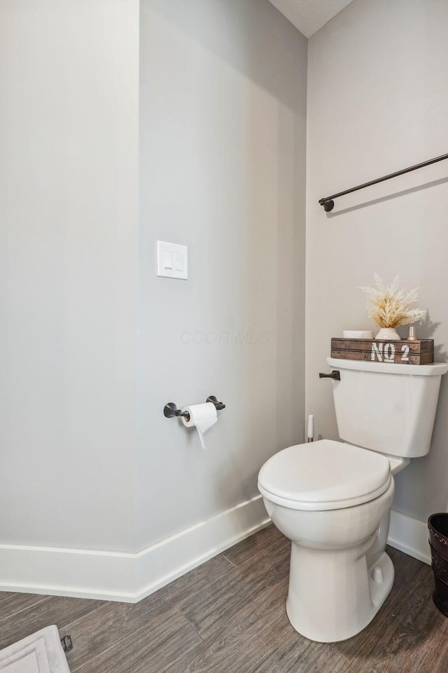 bathroom with toilet, baseboards, and wood finished floors