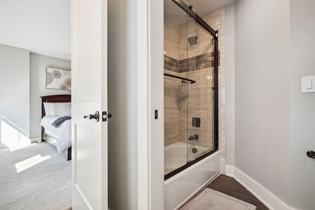 ensuite bathroom featuring connected bathroom, baseboards, and bath / shower combo with glass door