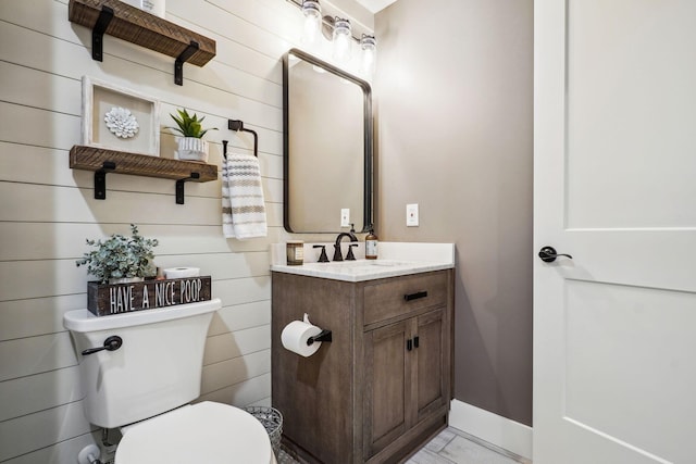 half bath featuring baseboards, toilet, and vanity