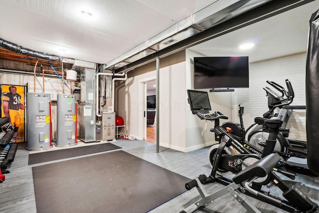 workout area featuring heating unit, electric water heater, and wood finished floors