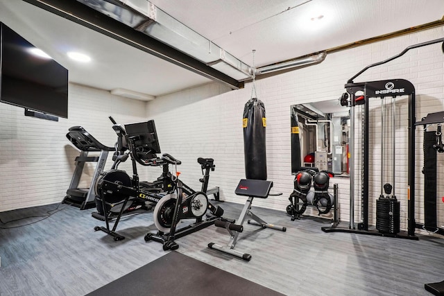 workout area with wood finished floors and brick wall