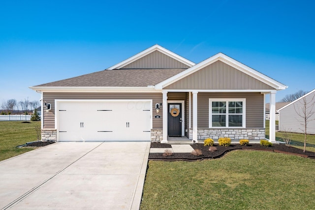 view of front facade with stone siding, driveway, a front yard, and roof with shingles