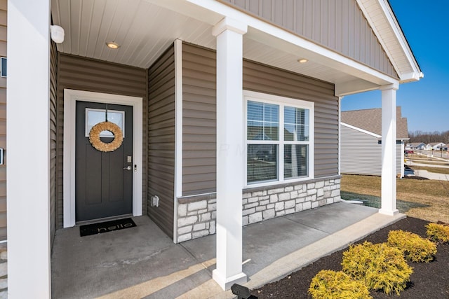 view of exterior entry featuring covered porch and stone siding