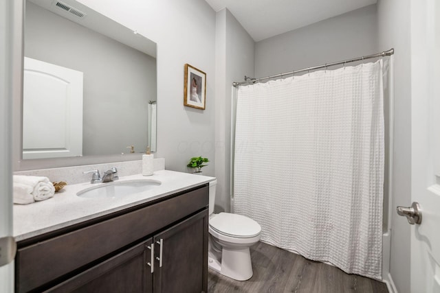 full bath featuring visible vents, shower / bath combo with shower curtain, toilet, wood finished floors, and vanity