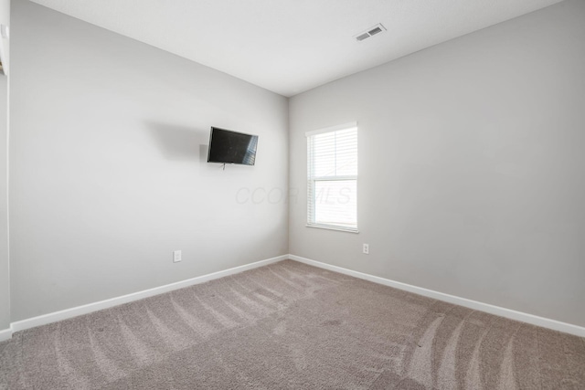 unfurnished room with carpet flooring, visible vents, and baseboards