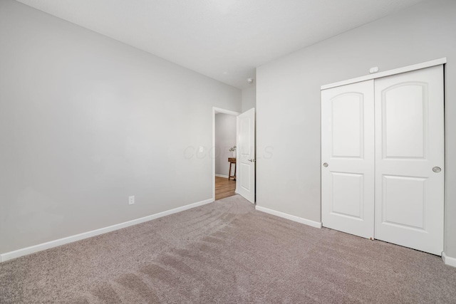 unfurnished bedroom with a closet, baseboards, and carpet flooring