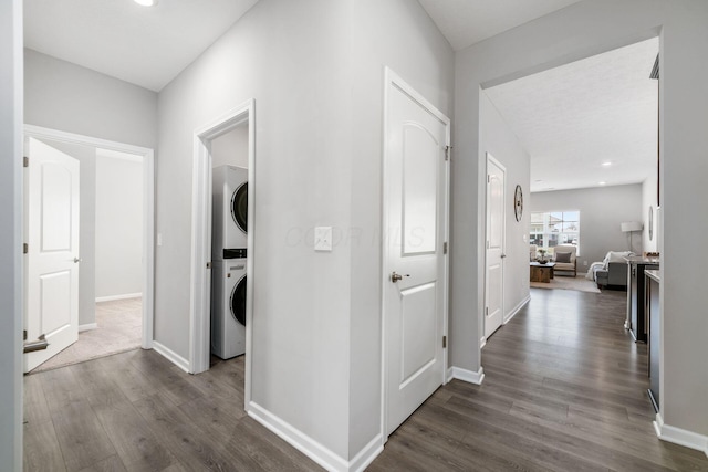 corridor with baseboards, dark wood-style flooring, and stacked washer / dryer