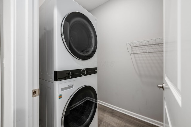 washroom with baseboards, dark wood-type flooring, laundry area, and stacked washing maching and dryer