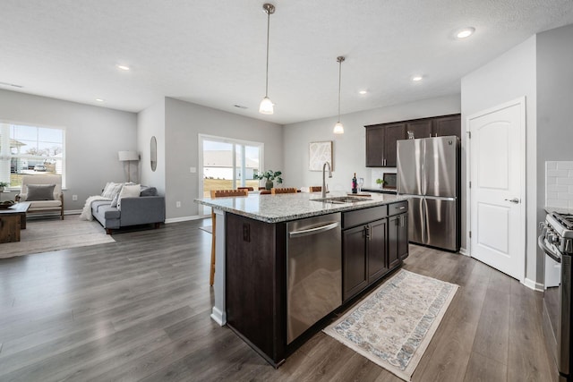 kitchen featuring dark wood-style flooring, a sink, stainless steel appliances, dark brown cabinets, and open floor plan