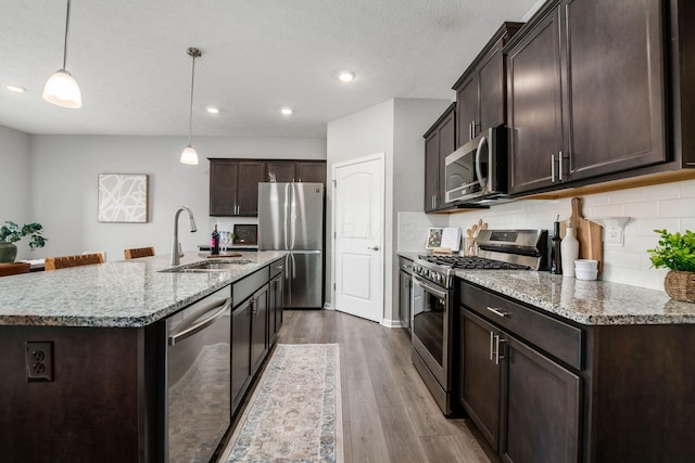 kitchen featuring a sink, tasteful backsplash, wood finished floors, appliances with stainless steel finishes, and dark brown cabinets