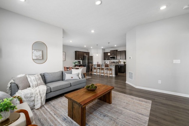 living room featuring dark wood finished floors, visible vents, recessed lighting, and baseboards