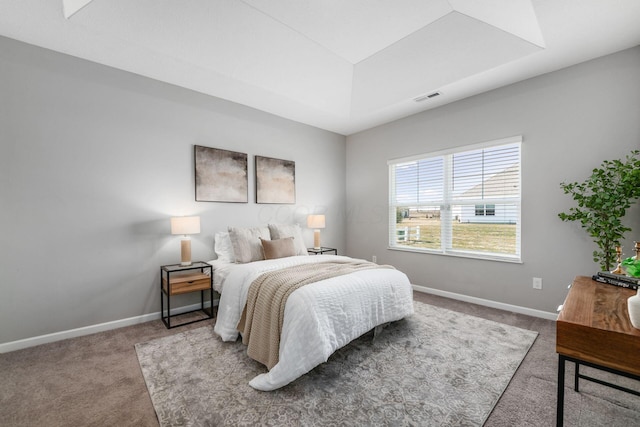 bedroom with a raised ceiling, carpet flooring, baseboards, and visible vents