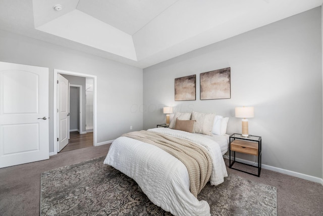 carpeted bedroom featuring baseboards and a raised ceiling