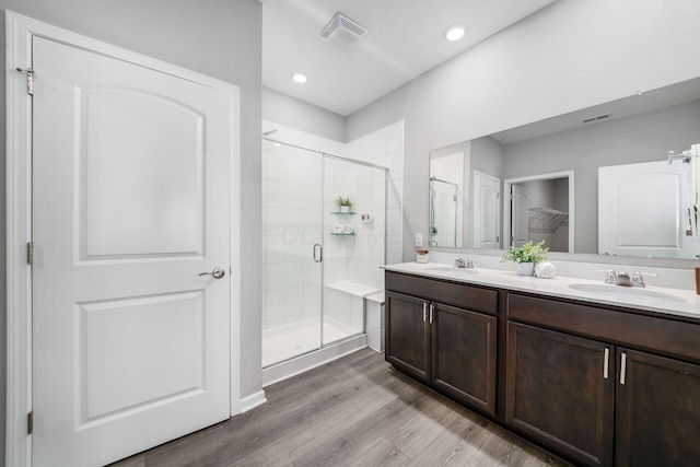 full bathroom with visible vents, a shower stall, wood finished floors, and a sink