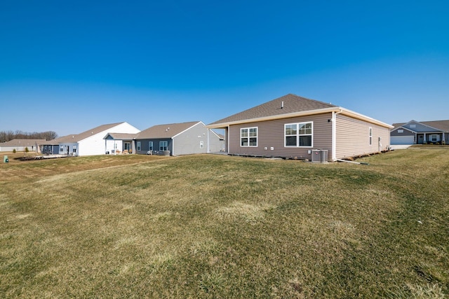 back of property with a yard, central air condition unit, and a residential view