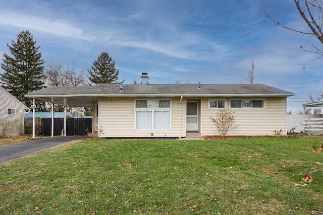 back of house with aphalt driveway, an attached carport, a lawn, and fence