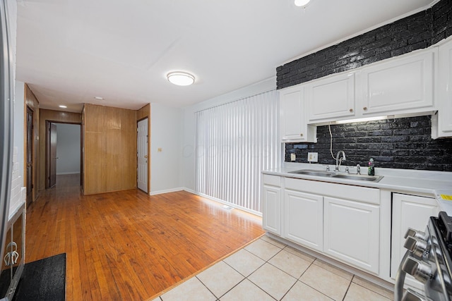 kitchen with light countertops, light tile patterned floors, gas stove, and a sink