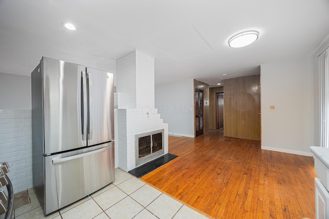 kitchen featuring recessed lighting, light wood-type flooring, freestanding refrigerator, and a large fireplace