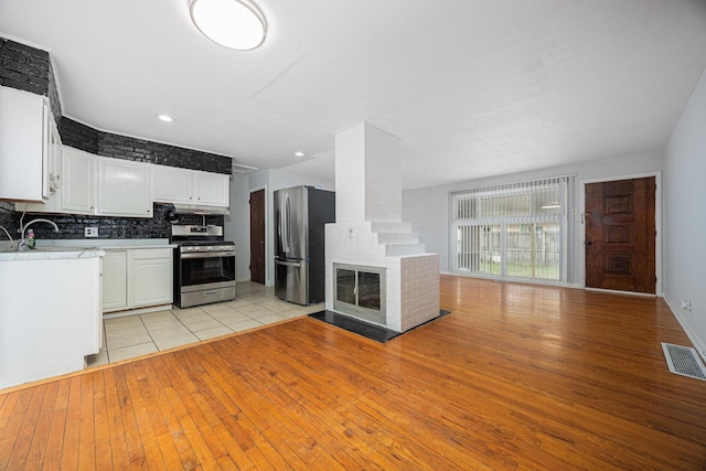 kitchen with visible vents, a sink, open floor plan, appliances with stainless steel finishes, and a fireplace