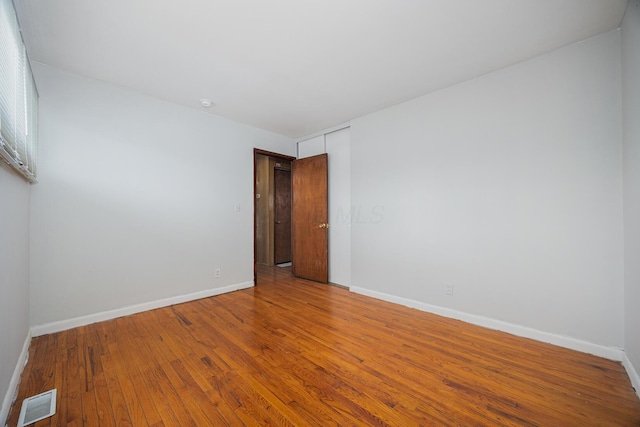 unfurnished room featuring visible vents, baseboards, and wood-type flooring