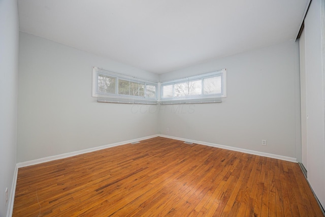 empty room featuring baseboards and wood-type flooring