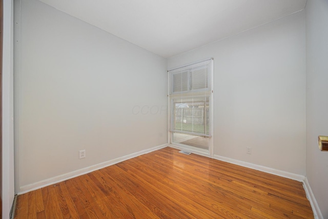 empty room with visible vents, baseboards, and wood finished floors