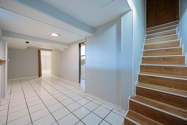 interior space featuring baseboards, light tile patterned flooring, and stairs