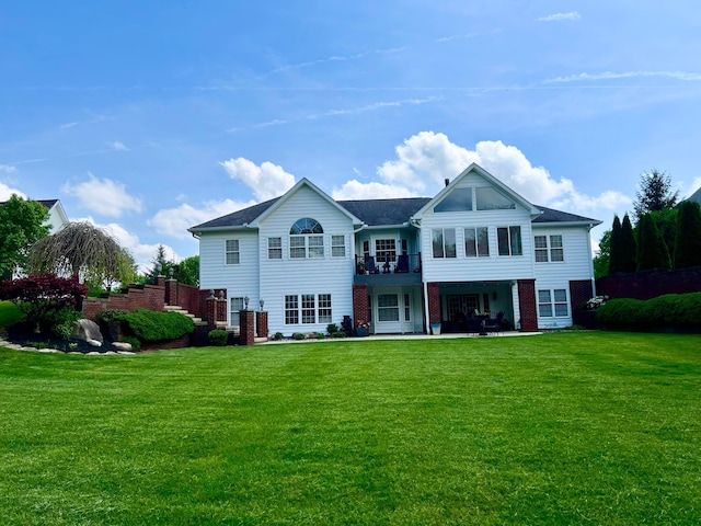 back of property with a lawn, brick siding, and a patio area