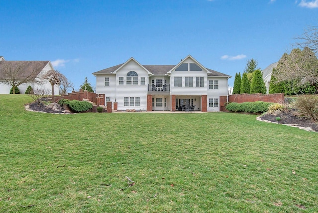 back of house with a patio area, a lawn, and brick siding