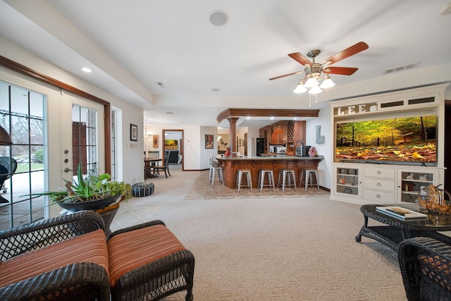 living room featuring visible vents, baseboards, light colored carpet, and ceiling fan