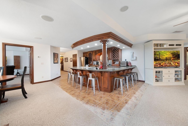 kitchen with a kitchen bar, light carpet, recessed lighting, a peninsula, and freestanding refrigerator