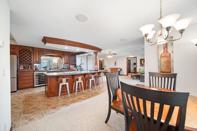 dining area with ceiling fan with notable chandelier, recessed lighting, wine cooler, light tile patterned floors, and bar