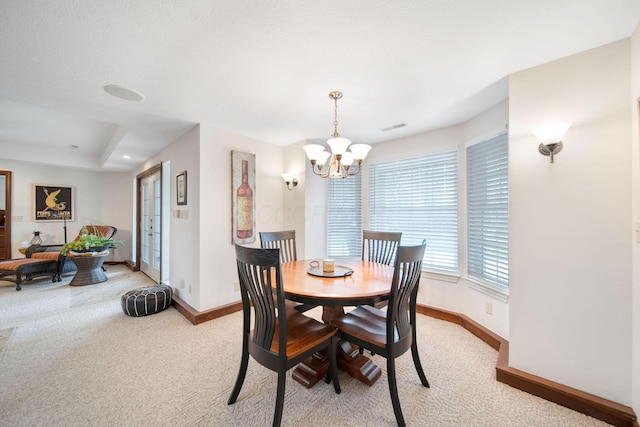dining area featuring an inviting chandelier, light colored carpet, visible vents, and baseboards