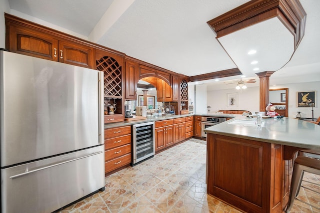kitchen featuring wine cooler, a breakfast bar, a peninsula, stainless steel appliances, and a sink