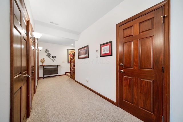 hall featuring visible vents, baseboards, and light colored carpet