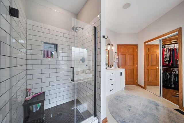 bathroom with tile patterned floors, a shower stall, vanity, and a walk in closet