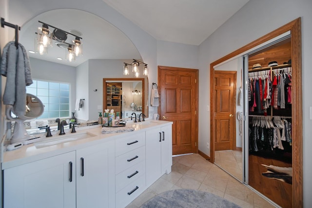 full bath with a walk in closet, double vanity, tile patterned floors, and a sink