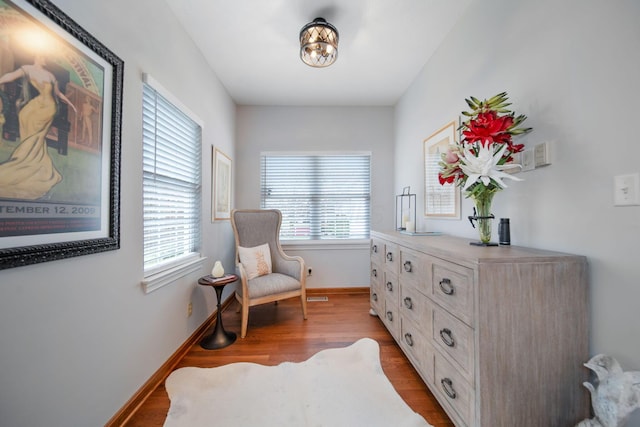 living area with visible vents, plenty of natural light, wood finished floors, and baseboards