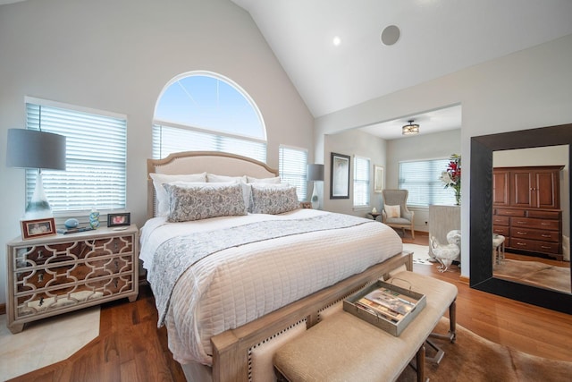 bedroom with high vaulted ceiling and wood finished floors