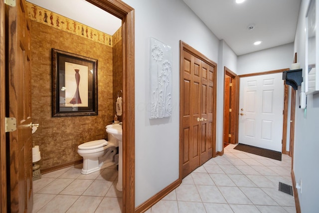 corridor with light tile patterned floors, visible vents, and baseboards