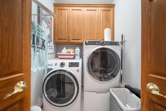 clothes washing area featuring cabinet space and washer and clothes dryer