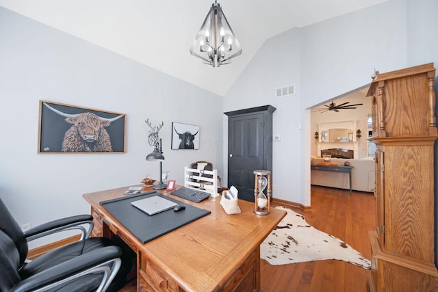 home office featuring visible vents, baseboards, ceiling fan with notable chandelier, wood finished floors, and high vaulted ceiling