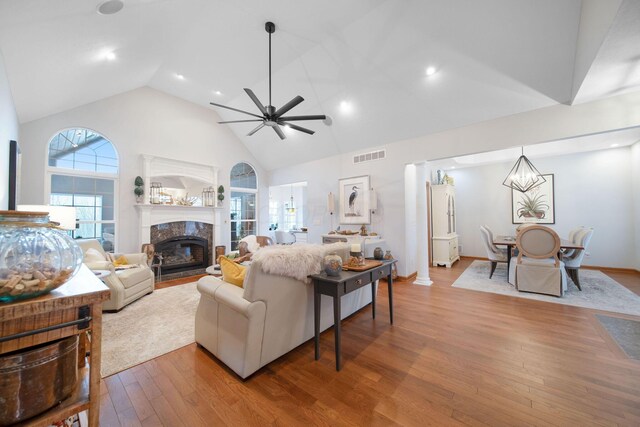 living room featuring visible vents, high vaulted ceiling, hardwood / wood-style flooring, a fireplace, and ceiling fan
